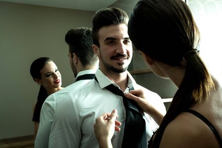A young couple preparing to go out and getting ready and dressed in the changing room.の写真素材