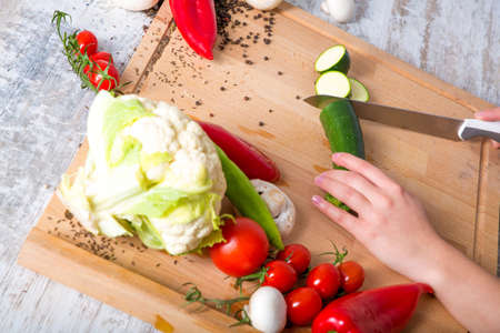 A woman chopping up vegetables at a table.の写真素材