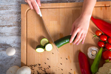 A woman chopping up vegetables at a table.の写真素材