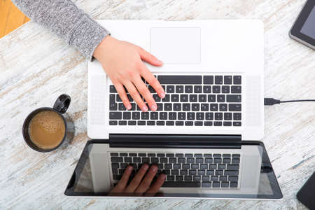 A working woman hand at a table with laptop tablet and phone.