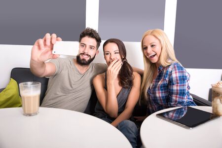 Friends siting at a table and taking a selfie in a coffee shop