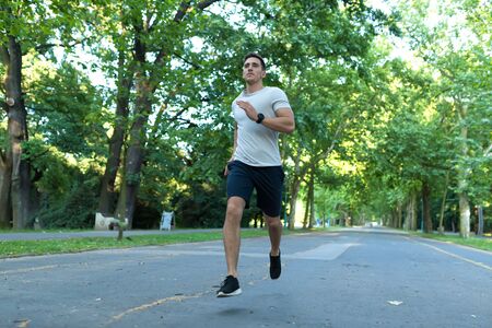 A handsome young man doing sports and jogging in a park.