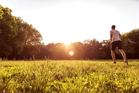 A handsome young man doing sports in the sunset in a park.の写真素材