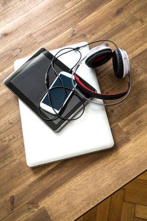 A Laptop computer, Headphones, a Tablet PC and a Smartphone on a wooden Desktop.の写真素材