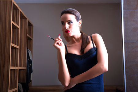 A young beautiful woman posing in front of a mirror with lipstickの写真素材