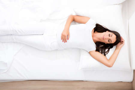 A young, beautiful woman relaxing in the bed at homeの写真素材