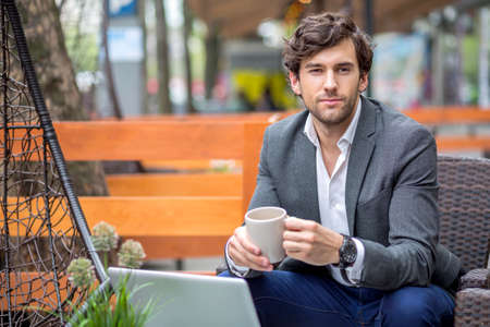 Portrait of a handsome young businessman siting on the terrace of a coffee shop.の写真素材