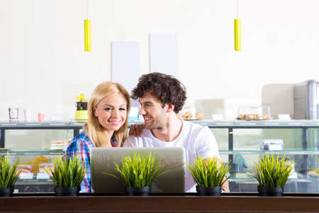 A beautiful young couple sitting in a coffee shop and using a laptopの写真素材