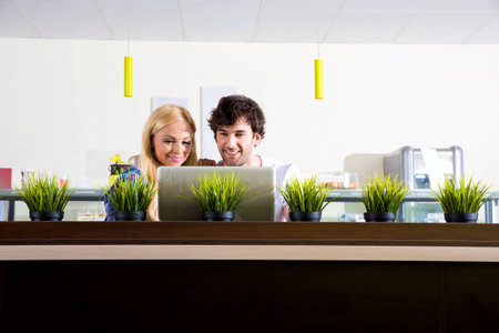 A beautiful young couple sitting in a coffee shop and using a laptopの写真素材
