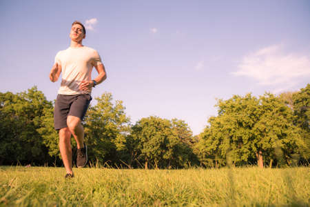 A handsome young man doing sports and running in a park.