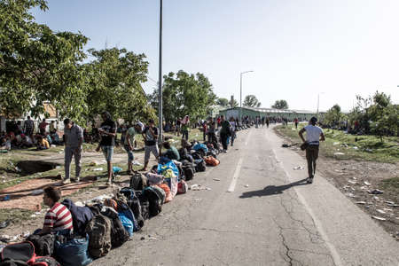 TOVARNIK, CROATIA - SEPTEMBER 18: Stranded Refugees form a waiting line with luggage after their arrival from Serbia on September 18, 2015 in Tovarnik, Croatia.のeditorial素材