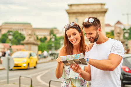 A beautiful young tourist couple are looking at a map  in Budapest, Hungary.の写真素材