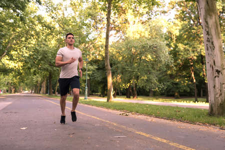 A handsome young man doing sports and jogging in a park.