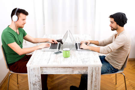 Two young men working in their home office