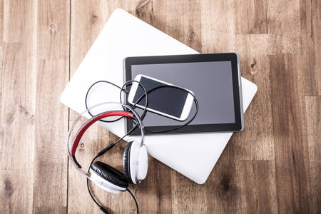 A Laptop computer, Headphones, a Tablet PC and a Smartphone on a wooden Desktop.の写真素材