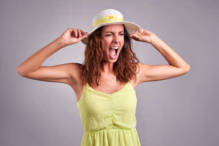 A beautiful young woman screaming in a green dress and a hatの写真素材