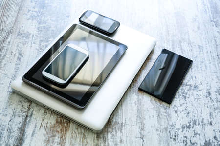 Various smartphones, a Laptop and Tablet Pcs on a wooden Table.の写真素材
