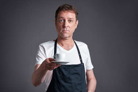 A middle age man serve a cup of coffeeの写真素材