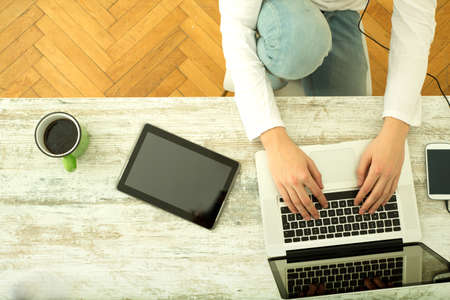 A young man using his laptop computer and various other devices at home.