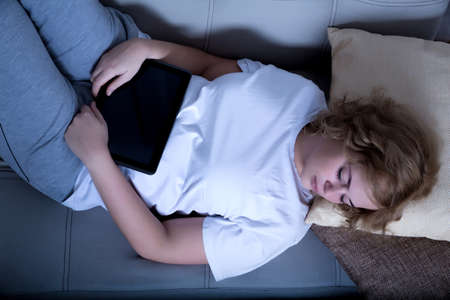 A young plus size woman fell asleep on a sofa with a Tablet PC at night.の写真素材