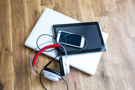 A Laptop computer, Headphones, a Tablet PC and a Smartphone on a wooden Desktop.の写真素材
