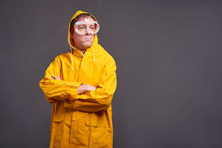 A serious middle aged man standing in a yellow raincoatの写真素材