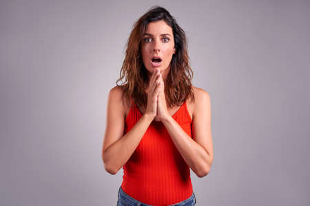 A beautiful young woman looking surprised in a red top