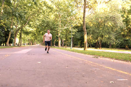 A handsome young man doing sports and jogging in a park.