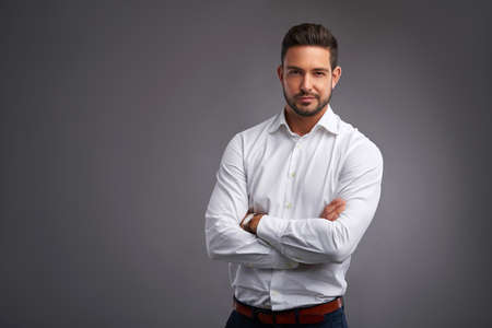 A handsome confident young man standing and smiling in a white shirt.の写真素材