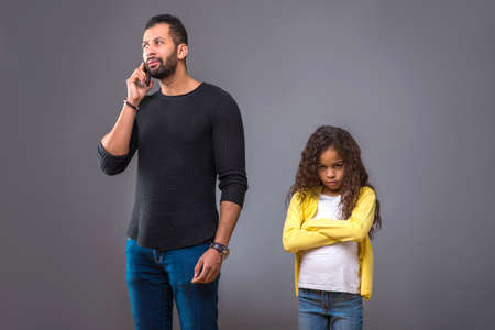 Black father talking on his phone while his daughter waitingの写真素材