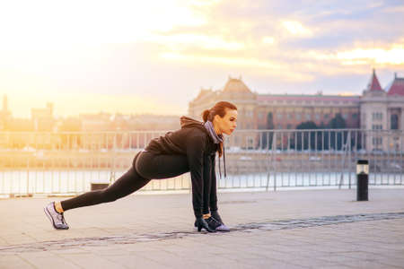 A sporty young woman stretching in the sunsetの写真素材