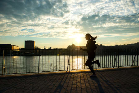 Young woman running in sunsetの写真素材