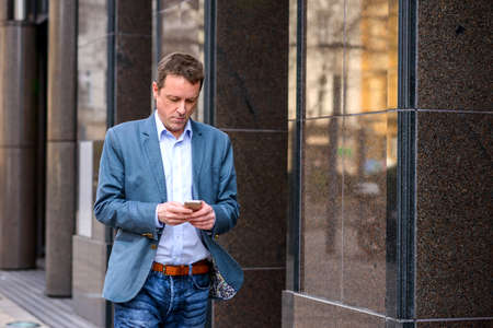 A middle age businessman walking with a phone
