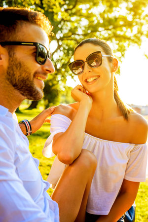 Beautiful young couple relaxing on a sunny summer day on a benchの写真素材