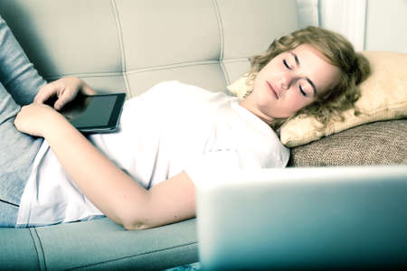A young plus size woman fell asleep on a sofa with a Tablet PC at night.