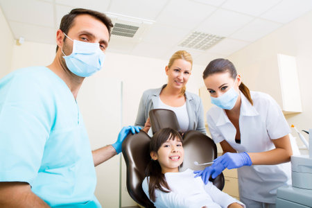 A little girl accompanied by her mother getting treatment at the dentist.の写真素材
