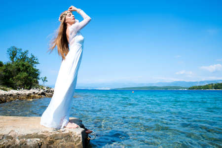 A young beautiful woman standing at the ocean in the summer.の写真素材