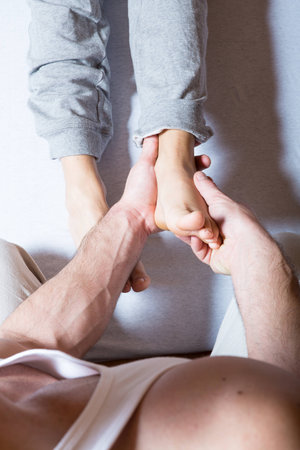A young adult woman receiving a foot massage by a male masseur.の写真素材