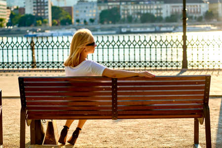 Young woman siting on a bench on the riversideの写真素材