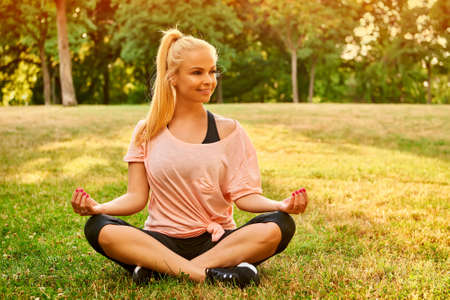 Young woman meditating on a field in a parkの写真素材