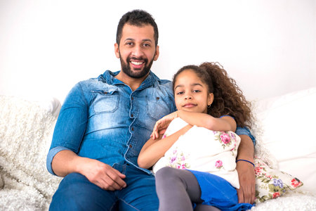 Black father and his daughter siting on a couchの写真素材