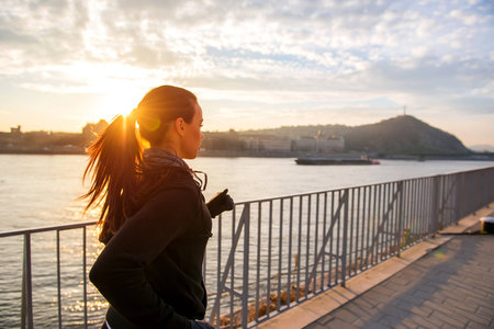 Young woman running in sunsetの写真素材