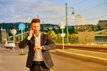 Young businessman walking on the street and talking on a phoneの写真素材