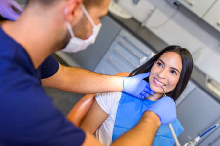 A young Dentist treating a female Patient in the dental studio