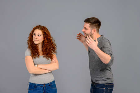A beautiful young couple standing and arguing in the studio