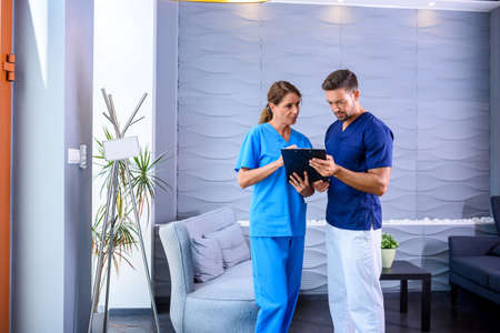 A Doctor discussing details of a medical procedure with his Assiの写真素材