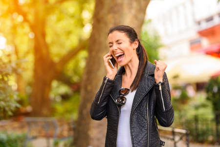 A happy young woman using her phone in a urban environment