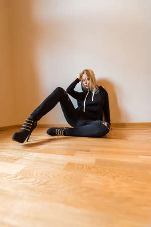 A beautiful young woman sitting on the floor and wearing black clothes.の写真素材