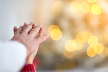A young couple holding hands at christmas with lights in the background.の写真素材