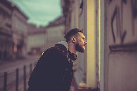 A retro style photo of a young hipster man checking a storefront in an urban environment.の写真素材